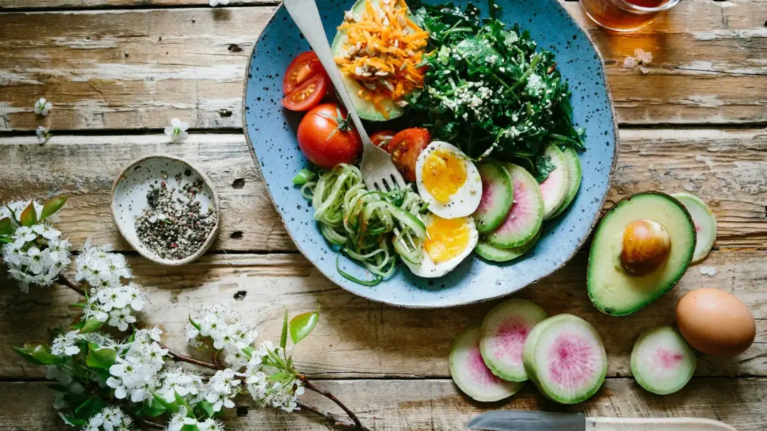 Mesa com prato colorido de vegetais, grãos e proteínas, luz natural