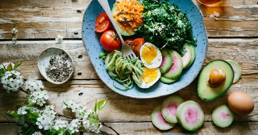 Tigela com folhas, ovo, abacate e vegetais, exemplo de refeição com fibras