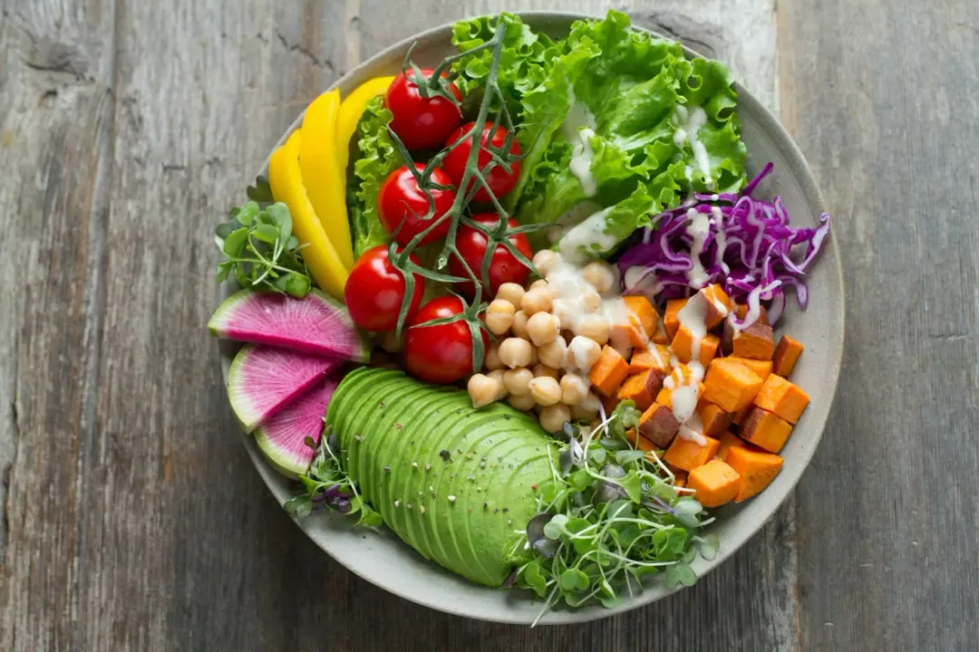 Prato colorido com folhas, legumes e proteínas, exemplo de refeição rica em fibras
